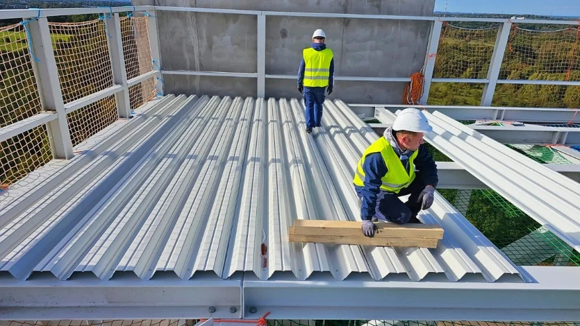 Radnici na krovu koji postavljaju limeni krov i konstrukciju.